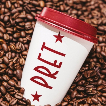 Pret Express takeaway cup sitting on a pile of coffee beans